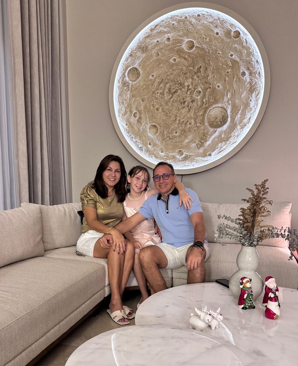 Familia con escultura de luna Lunático hiperrealista en sala de lujo