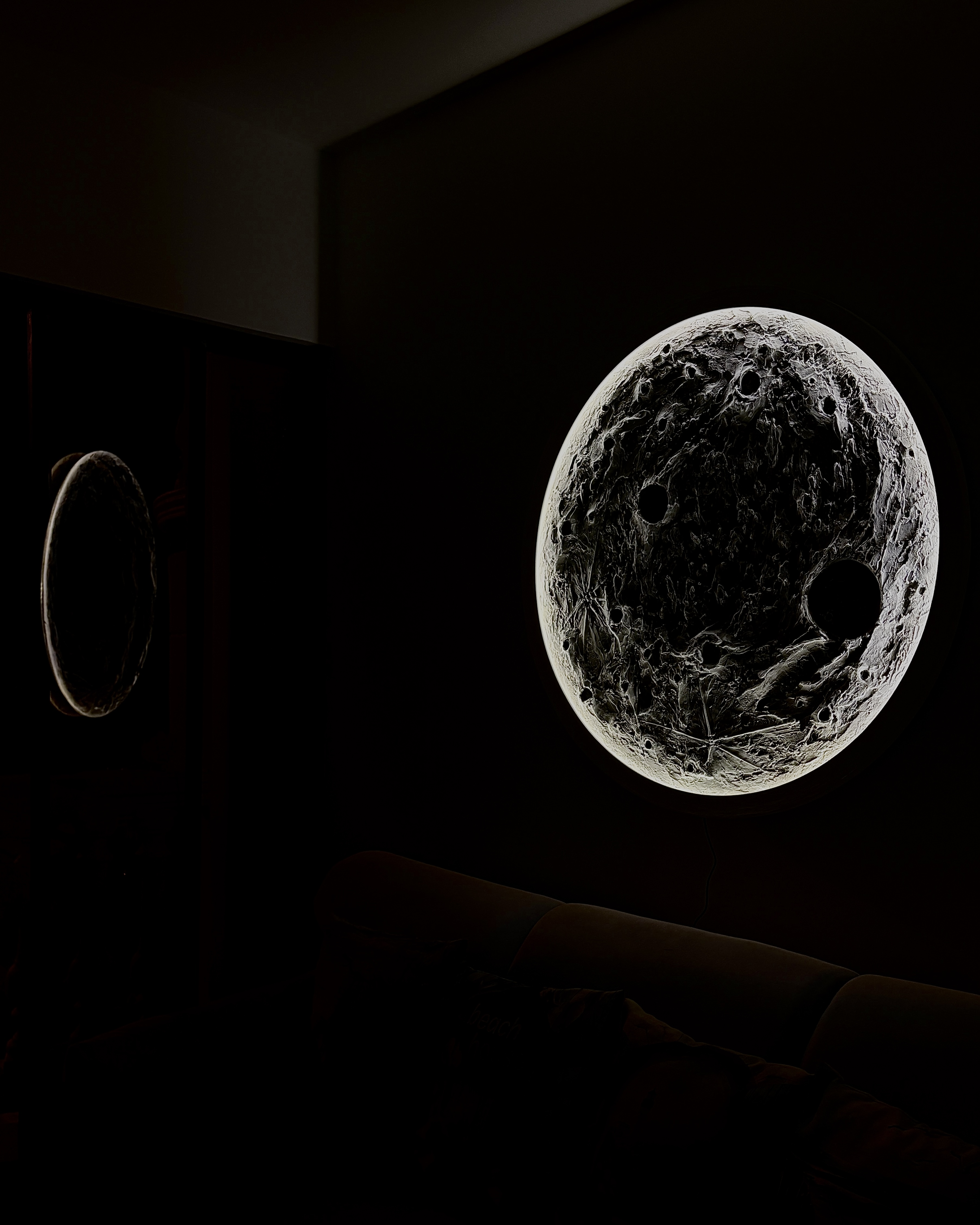 Escultura lunar Lunático encendida en sala oscura — efecto de luz ambiental